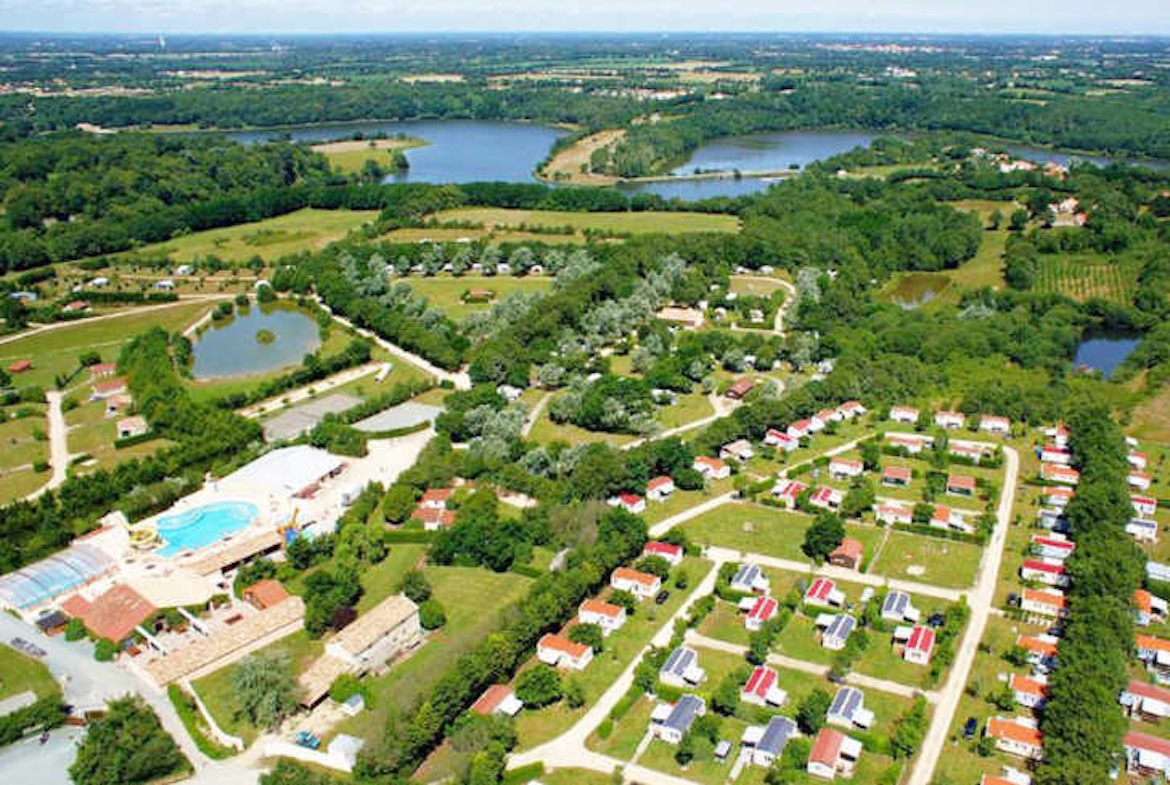 Aerial view of Camping Village de la Guyonnière in the Vendée, featuring pools, open green spaces, and family friendly facilities